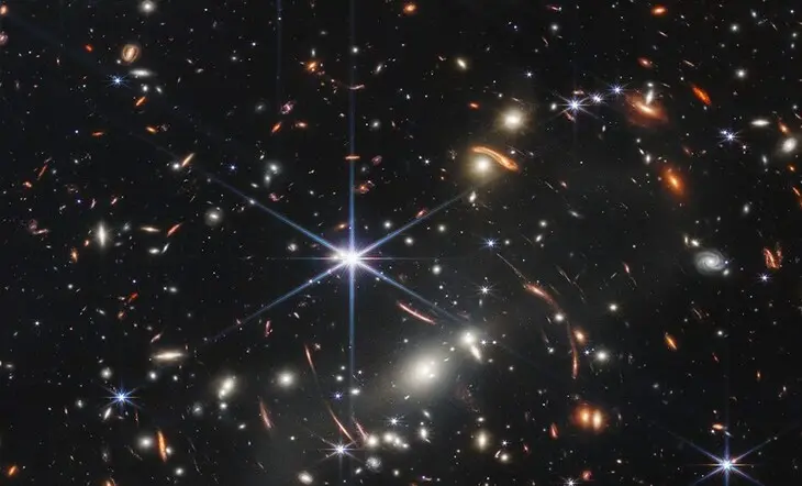 Los arcos rojos en la imagen rastrean la luz de las galaxias en el Universo muy primitivo. Fuente NASA