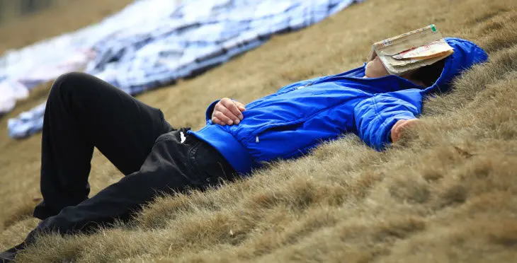 JIUJIANG, CHINA - MARCH 12: (CHINA OUT) A student sleeps with a book covering his face as sheets laid on the ground are aired in the sun at Jiujiang University on March 12, 2012 in Jiujiang, Jiangxi Province of China. After a long winter vacation returning Chinese students will air their sheets, duvets and clothes in the grounds of the halls of residence to help freshen them up. (Photo by ChinaFotoPress/ChinaFotoPress via Getty Images)