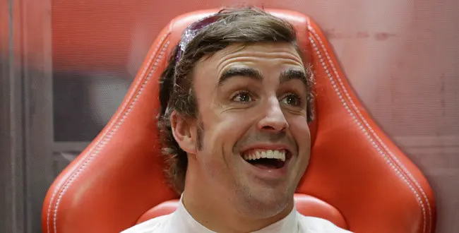 Ferrari driver Fernando Alonso jokes with his team mechanics in his team garage during the first practice session at the Indian Formula One Grand Prix at the Buddh International Circuit in Noida, India, Friday, Oct. 25, 2013.
