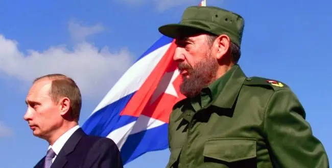 Russian President Vladimir Putin, left, and President Fidel Castro walk past a Cuban flag during Putin's official arrival ceremony in Havana, Cuba Thursday, Dec. 14, 2000. Putin is on a two-day trip to Cuba, the first visit of a Russian leader since the fall of the former Soviet Union. (AP Photo/Alexander Zemlianichenko)