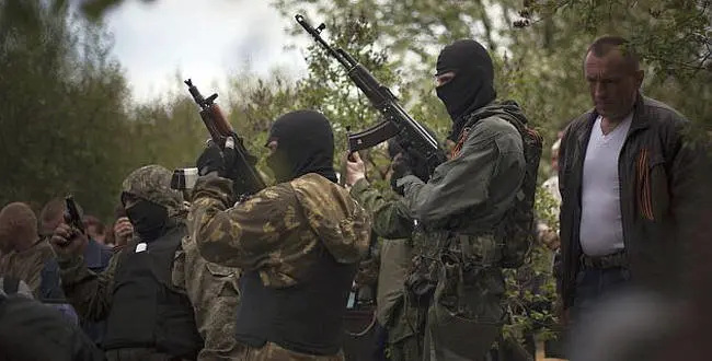 Masked pro Russia militia fire a salvo into the air to honor Pavel Pavelko, 42, one of three pro Russia militamen killed last Sunday in a shooting by unknown gunmen at a checkpoint, during his burial in Alexandrovska village, 15 kilometers (9.3 miles) from Sloviansk, Ukraine, Tuesday, April 22, 2014. (AP Photo/Manu Brabo)
