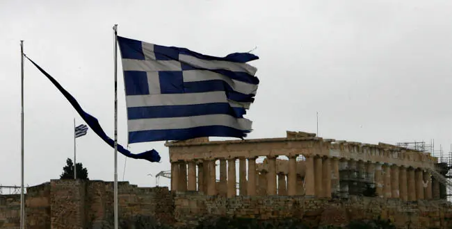 The flags of Greece, right, and European flag in tatters as they flutter from the roof of the Finance Minister at Athens' main Syntagma square, as in the background is seen the ancient Parthenon temple during a 24-hour strike on Tuesday, Feb. 7, 2012.