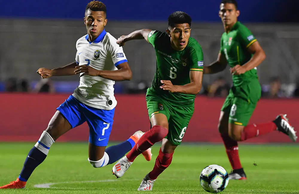 Bolivia's Erwin Saavedra (C) is followed by Brazil's David Neres during their Copa America football tournament group match at the Cicero Pompeu de Toledo Stadium, also known as Morumbi, in Sao Paulo, Brazil, on June 14, 2019. (Photo by Nelson ALMEIDA / AFP)