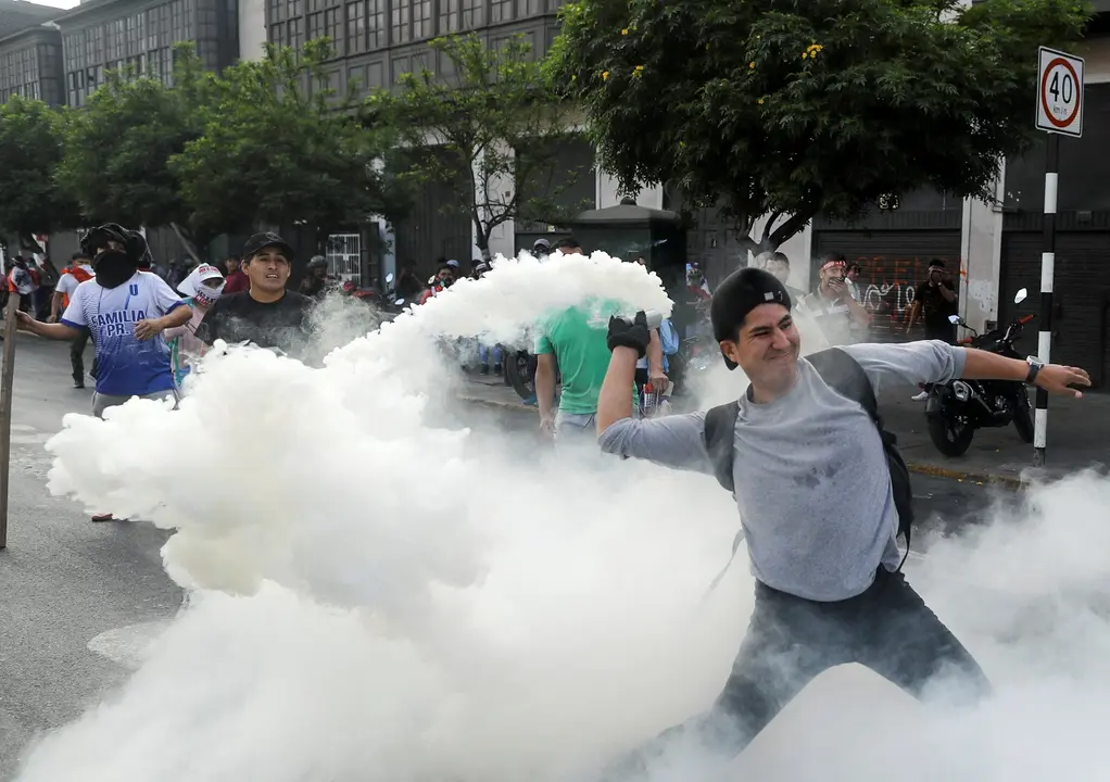 Un manifestante se prepara para devolver un bote de gas lacrimógeno durante una protesta exigiendo la disolución del Congreso y celebrar elecciones democráticas en lugar de reconocer a Dina Boluarte como presidenta de Perú, tras la destitución del presidente peruano Pedro Castillo, en Lima, Perú. 12 de diciembre, 2022. REUTERS/Sebastian Castaneda