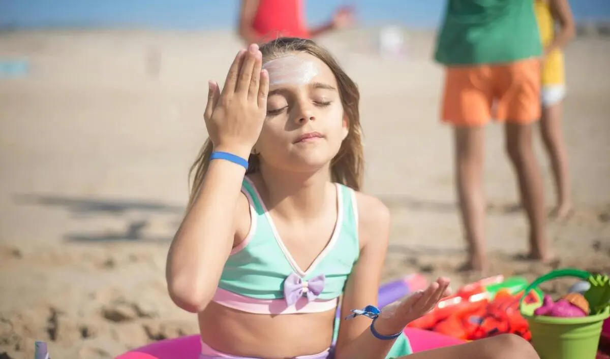 Niña aplicándose crema solar | Fuente: Pexels