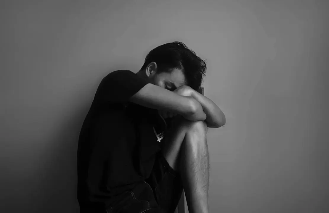 Hombre cabizbajo sentado | Fuente: Pexels