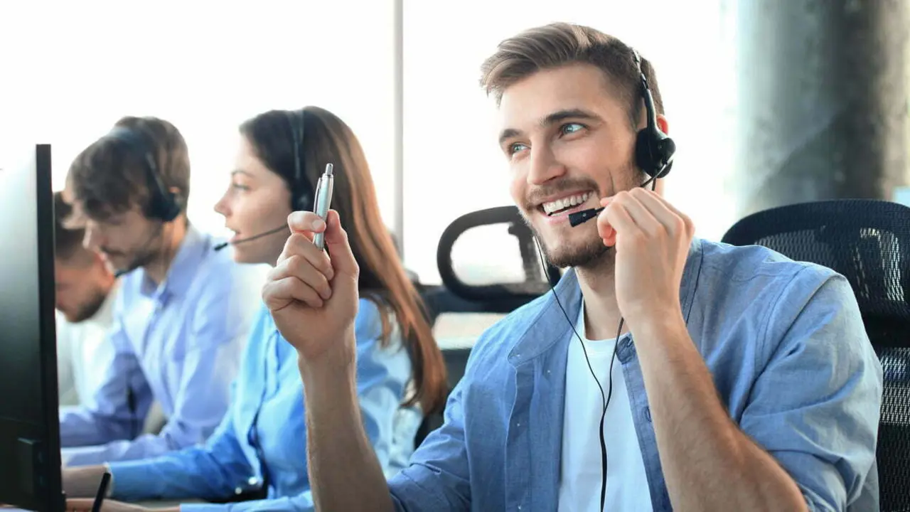 Portrait of call center worker accompanied by his team. Smiling customer support operator at work