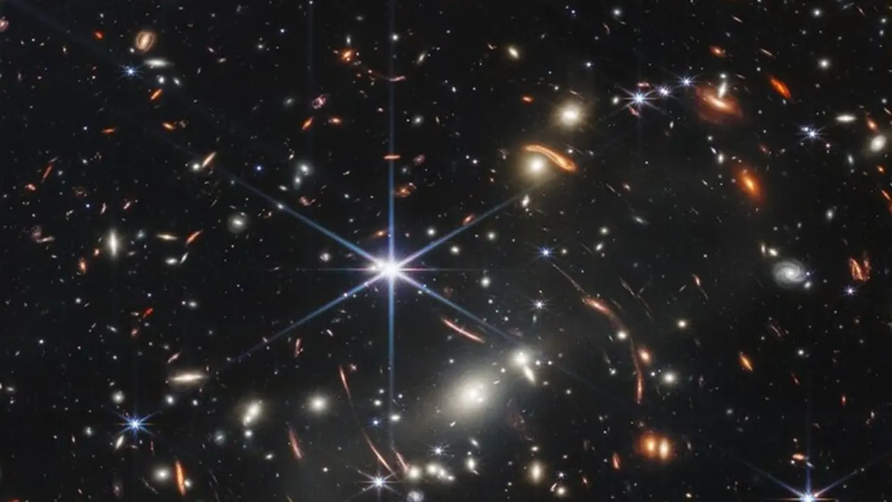Los arcos rojos en la imagen rastrean la luz de las galaxias en el Universo muy primitivo. Fuente NASA