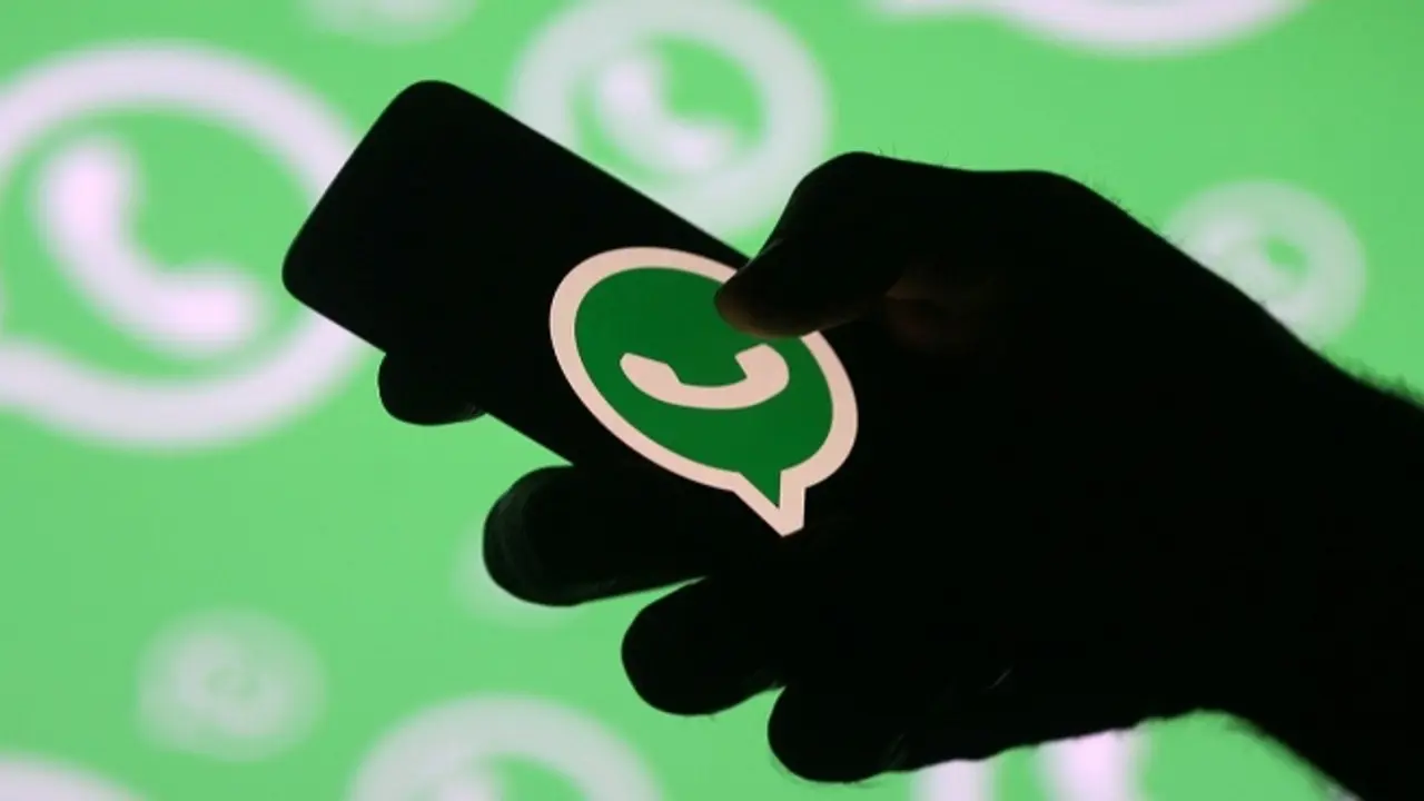 A man poses with a smartphone in front of displayed Whatsapp logo in this illustration September 14, 2017. REUTERS/Dado Ruvic - RC1740C10AC0