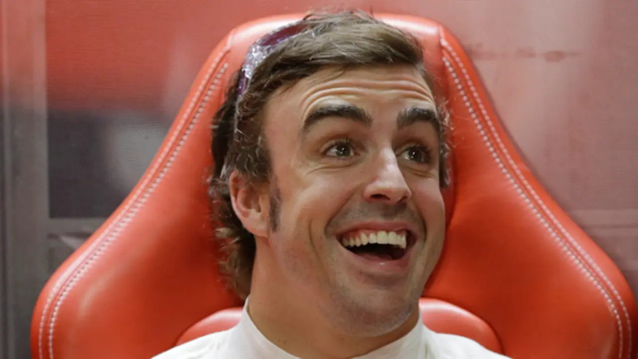 Ferrari driver Fernando Alonso jokes with his team mechanics in his team garage during the first practice session at the Indian Formula One Grand Prix at the Buddh International Circuit in Noida, India, Friday, Oct. 25, 2013.