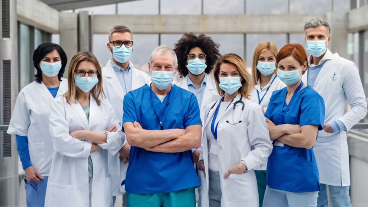 A group of doctors with face masks looking at camera, corona virus concept.