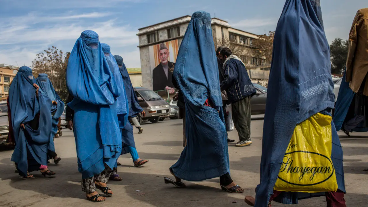 KABUL, AFGHANISTAN - NOVEMBER 07:  Afghan women walk through the street, as a poster of President Hamid Karzai is seen on the outside City Hall on November 7, 2012 in Kabul, Afghanistan. (Photo by Daniel Berehulak/Getty Images)