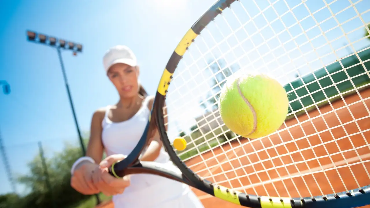 young sporty female tennis player hitting the ball