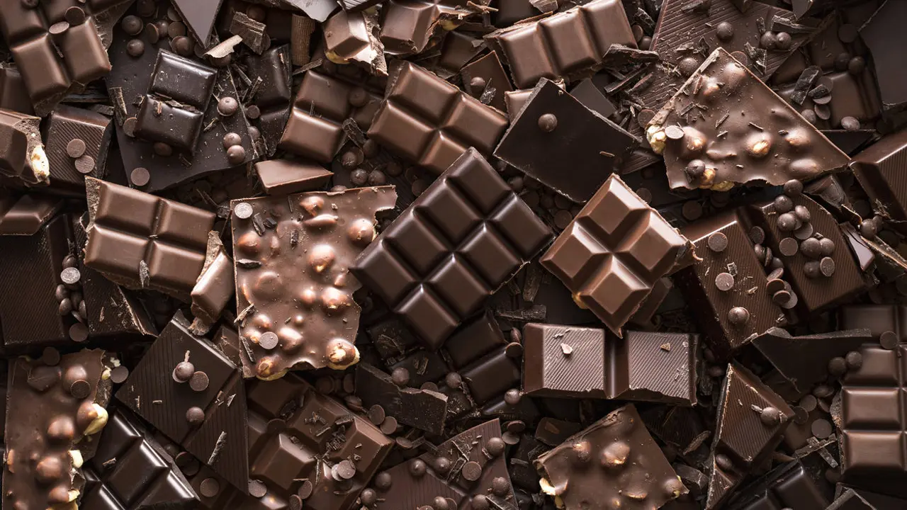 Assorted chocolate bar and chunks, background. Flat lay with a multitude of chocolate kinds. Delicious cocoa dessert. Baking chocolate collection.
